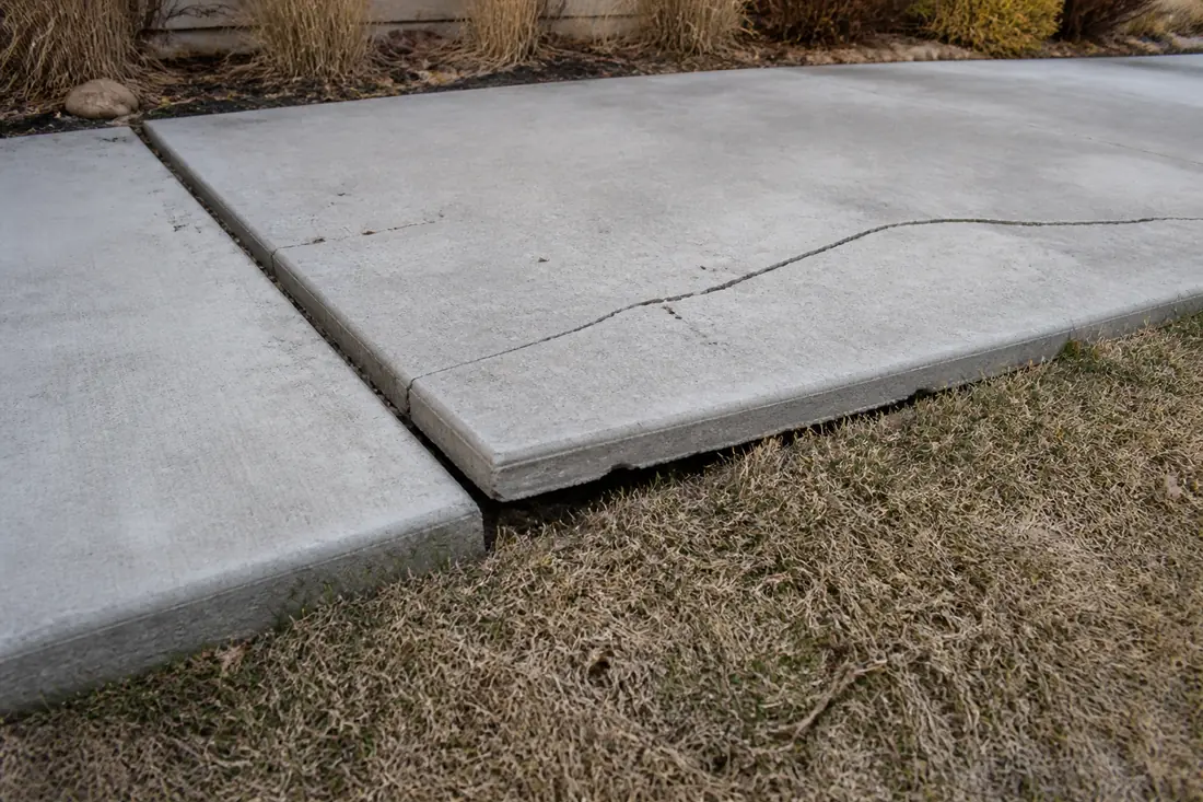 A concrete slab lifted and cracked where the ground beneath it has moved