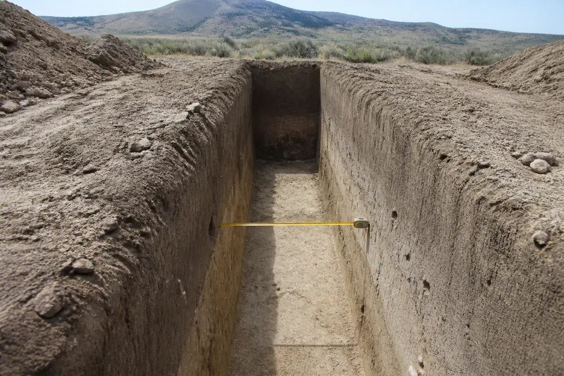 An excavated strip footing trench with square cut faces and a tape measure stretched across it