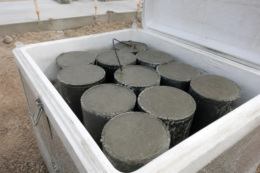 Concrete test cylinders standing in a curing box on a building site